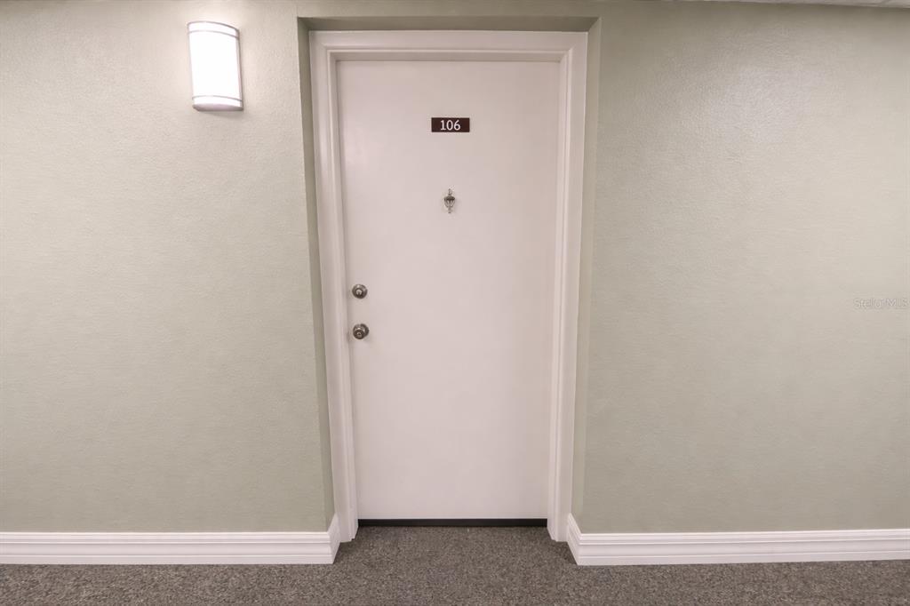 A white apartment door labeled 106 is centered on a light green wall — 21280 BRINSON AVENUE UNIT 106, PORT CHARLOTTE, FL