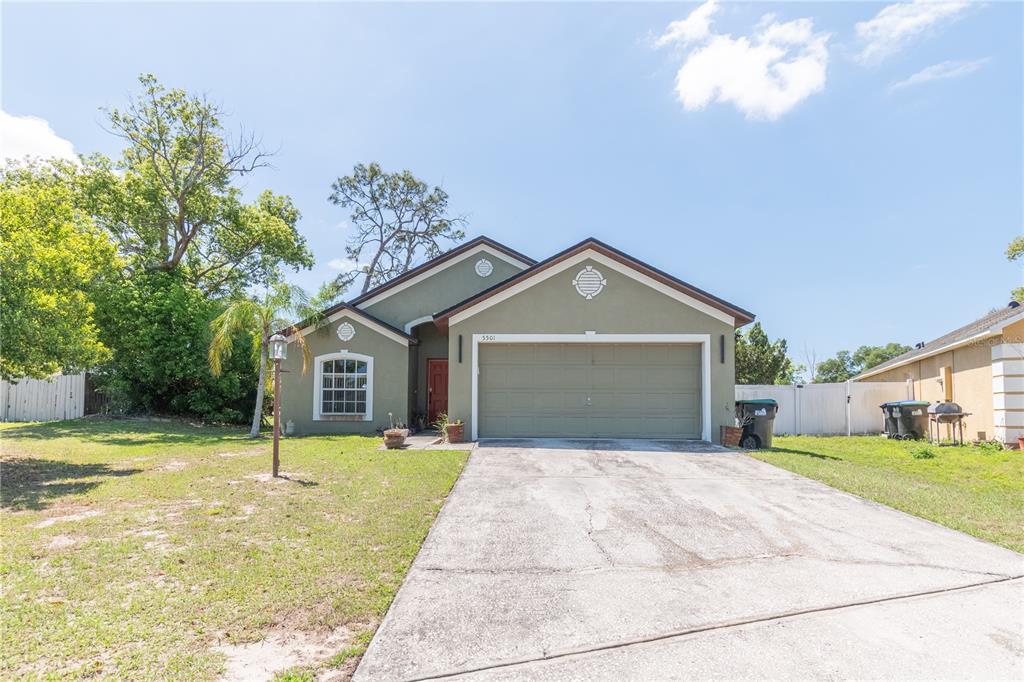 A single-story house with a green exterior, a two-car garage, and a concrete driveway — 5501 CHATHAM WOODS COURT, ORLANDO, FL