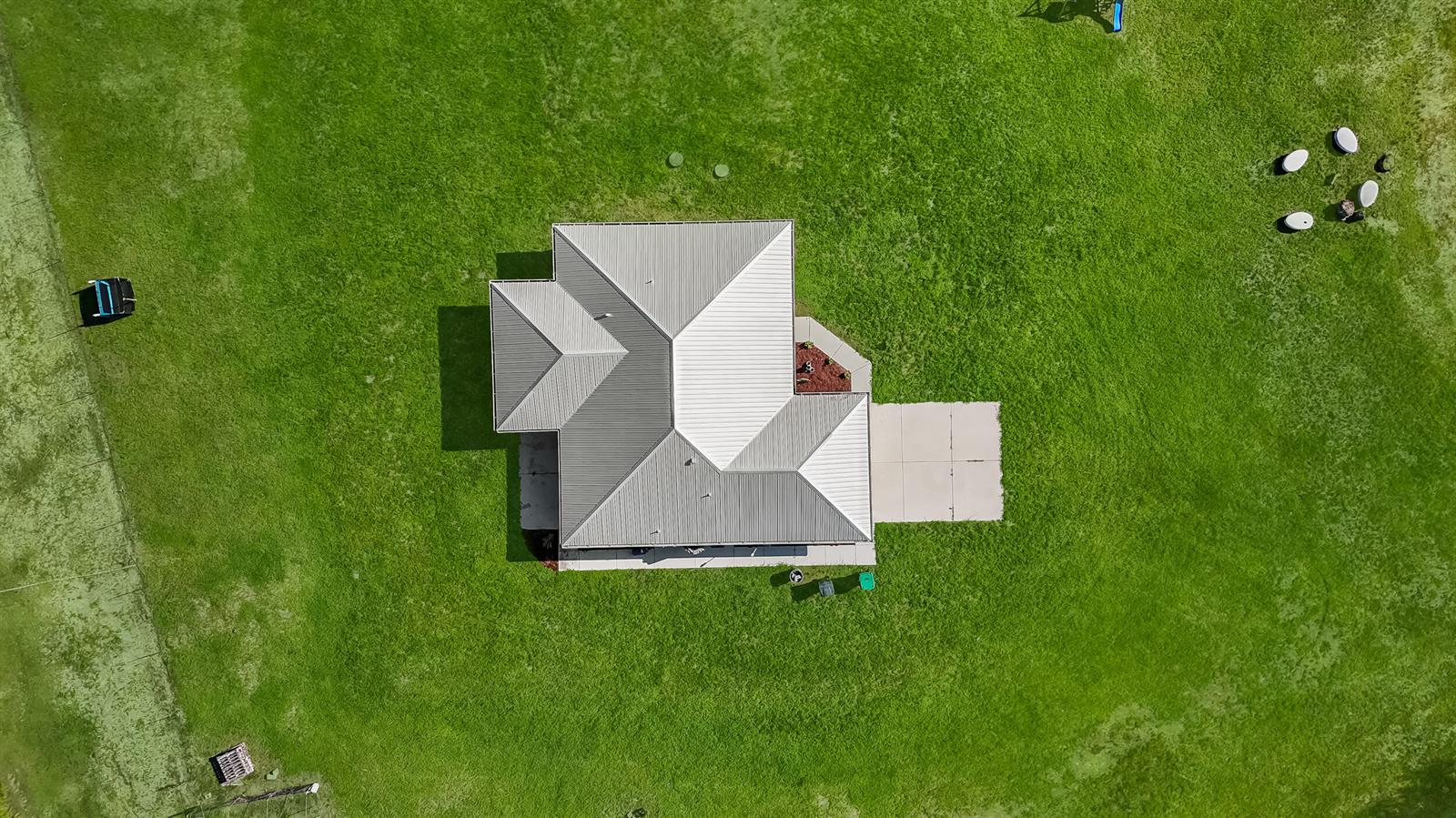 An aerial view shows a house with a metal roof surrounded by a large green lawn — 2872 Secretariat Drive, FL 33935, FL
