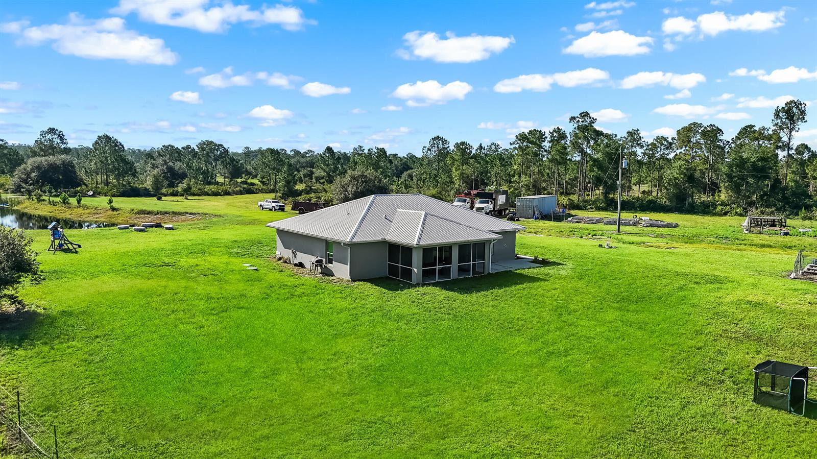 An aerial view shows a gray house with a metal roof situated on a large lawn — 2872 Secretariat Drive, FL 33935, FL