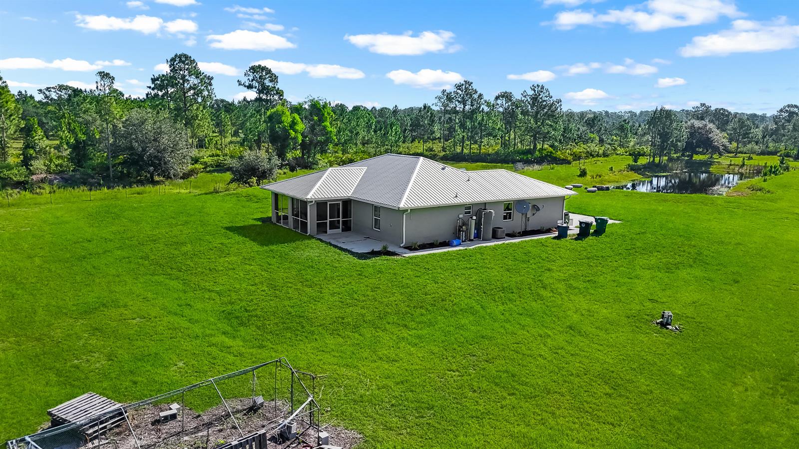 An aerial view shows a single-story house with a metal roof situated on a lawn — 2872 Secretariat Drive, FL 33935, FL