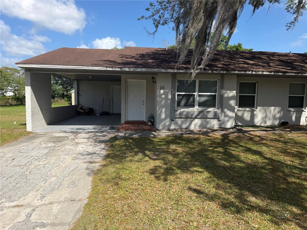 A single-story duplex with a concrete driveway, a carport, and a white front door — 2121 S SAN GULLY ROAD UNIT 14 - 15, LAKELAND, FL