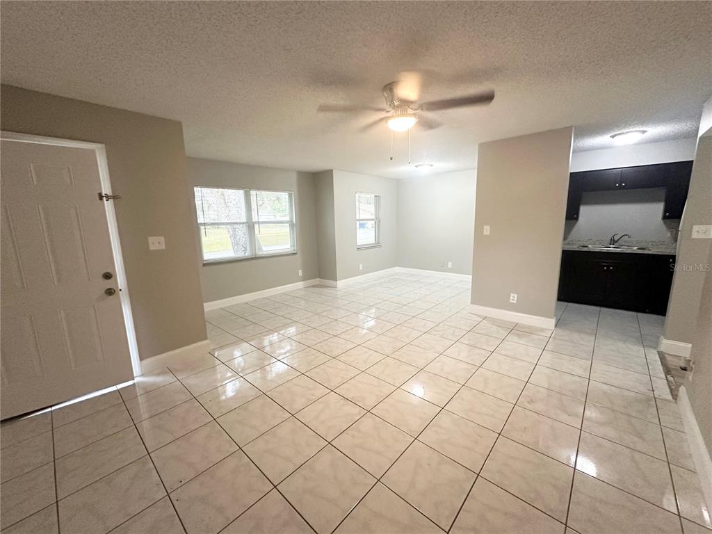 An open-concept living area features light-colored tile flooring, neutral walls, and an adjacent kitchen — 2121 S SAN GULLY ROAD UNIT 14 - 15, LAKELAND, FL