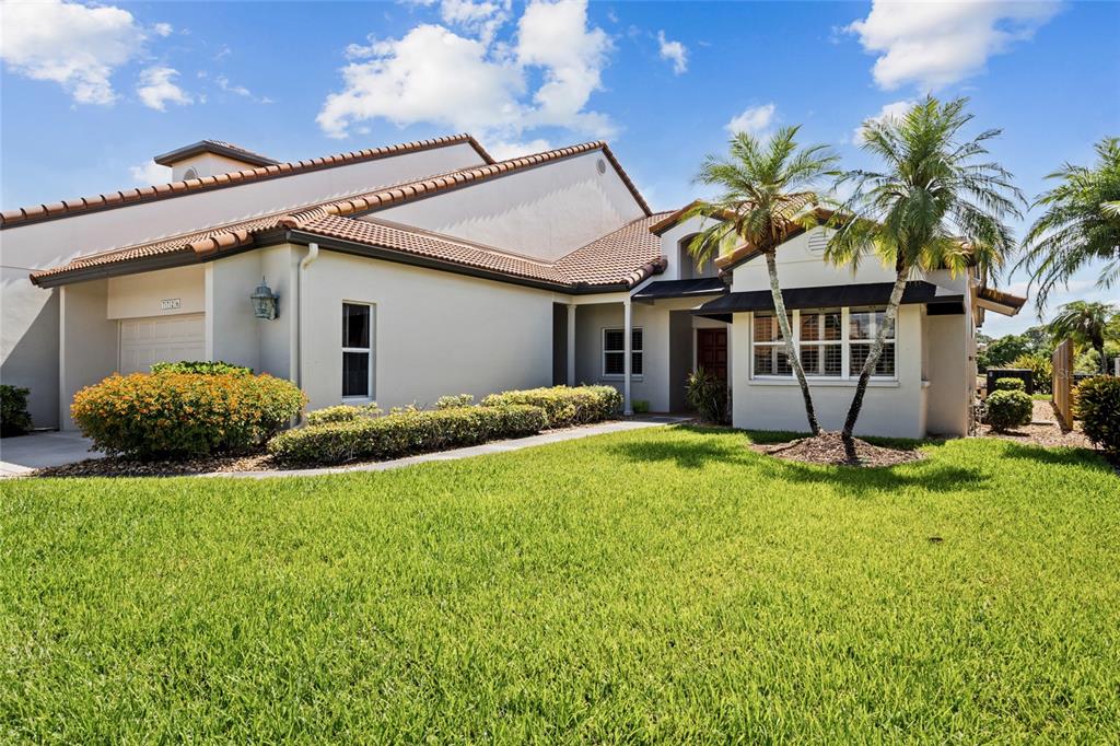 A single-story house with a tiled roof, palm trees, and a green lawn — 7726 CALLE FACIL, SARASOTA, FL