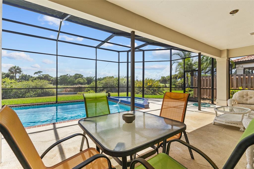 A covered patio features a dining set, a swimming pool, and a screened-in enclosure — 7726 CALLE FACIL, SARASOTA, FL