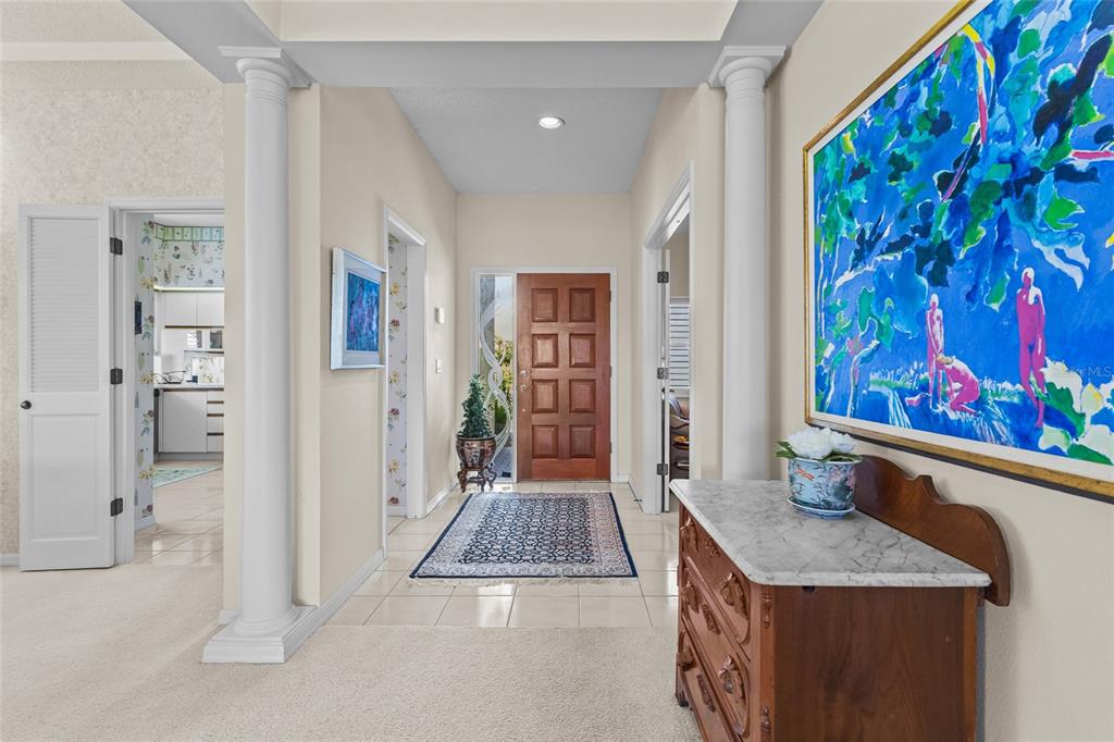 A foyer features a wooden front door, marble-topped chest, and two white columns — 7726 CALLE FACIL, SARASOTA, FL