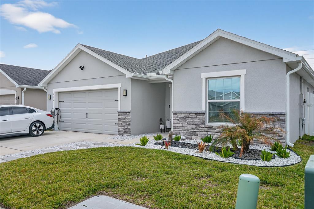 A single-story house with a gray stucco exterior, stone accents, and a two-car garage — 226 POLERMO AVENUE, ST CLOUD, FL