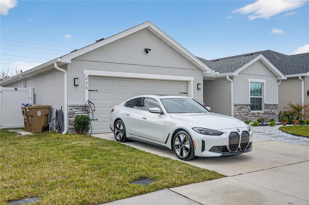 A white BMW sedan is parked in the driveway of a single-story suburban house — 226 POLERMO AVENUE, ST CLOUD, FL