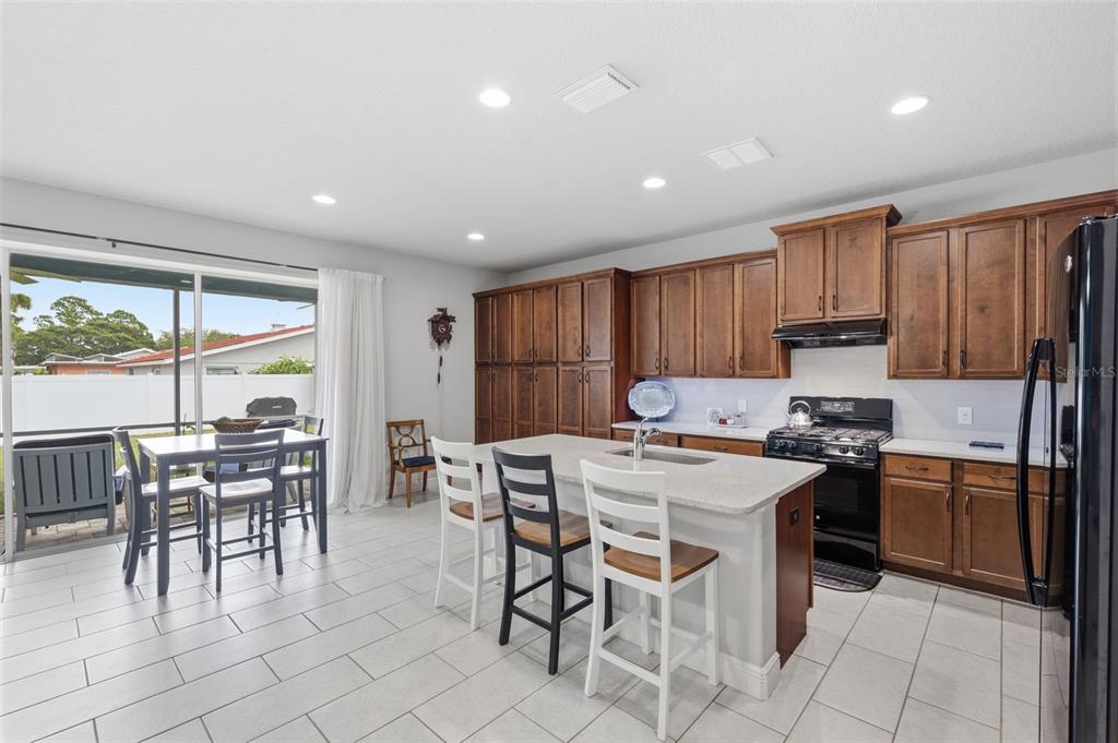 A kitchen with wood cabinets, a central island with seating, and a dining area nearby — 123 N FLORIDA AVENUE, TARPON SPRINGS, FL