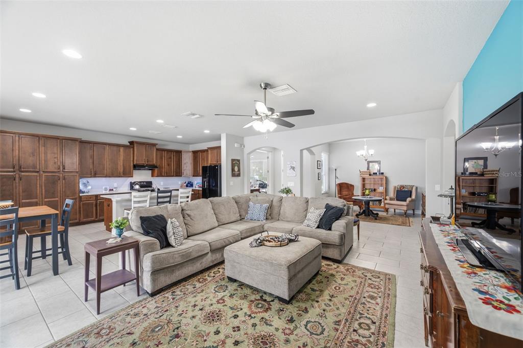 An open-concept living room features a large sectional sofa, kitchen cabinetry, and tile flooring — 123 N FLORIDA AVENUE, TARPON SPRINGS, FL