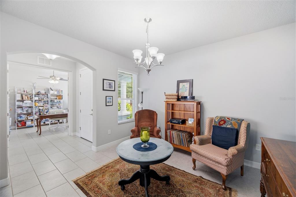 A sitting room features a chandelier, a round table, two armchairs, and a wooden bookshelf — 123 N FLORIDA AVENUE, TARPON SPRINGS, FL
