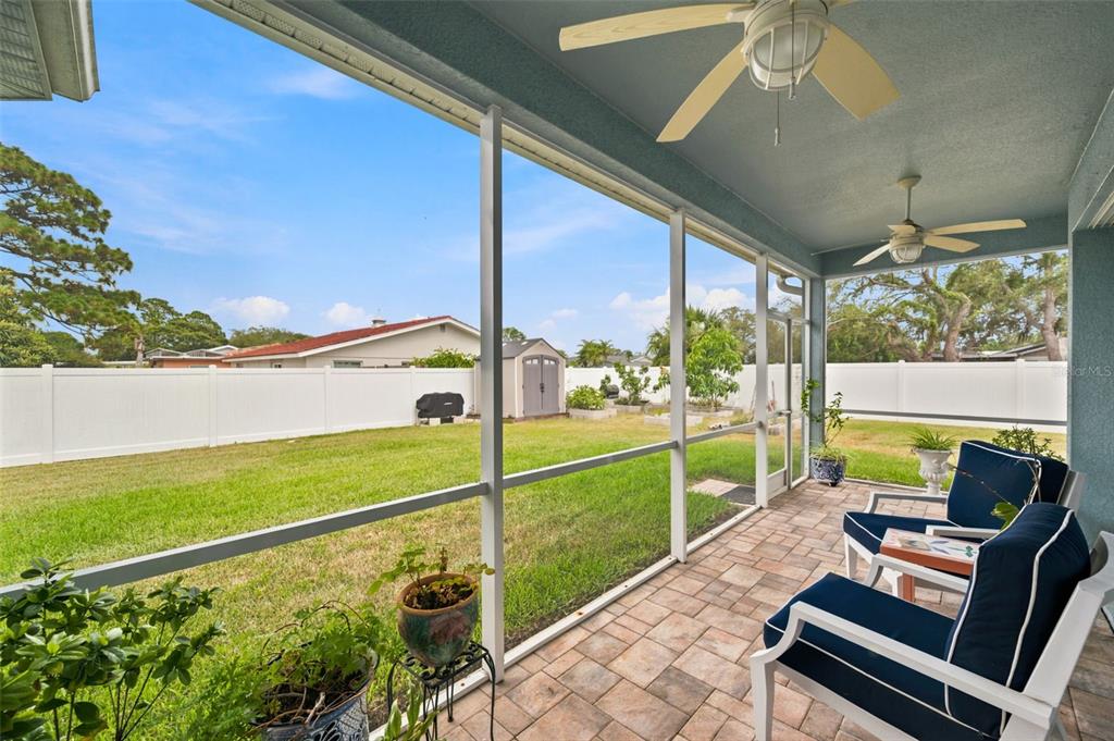 A screened-in patio with paver flooring overlooks a grassy backyard enclosed by a white fence — 123 N FLORIDA AVENUE, TARPON SPRINGS, FL
