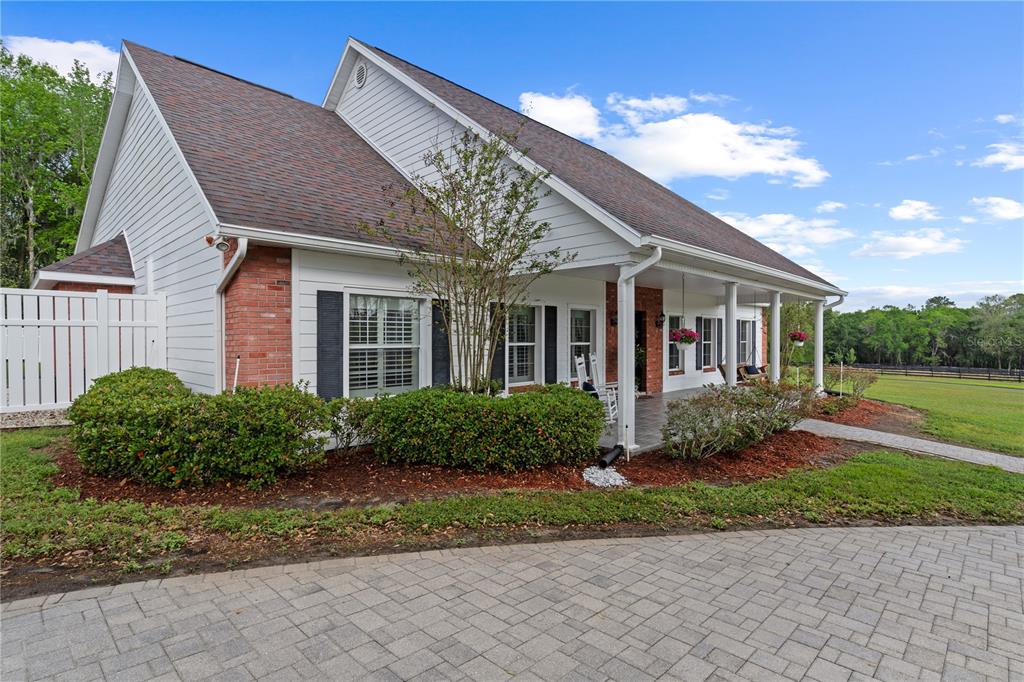 A white house with a brick facade and a covered front porch sits on a lot — 12345 CITRUS WAY, BROOKSVILLE, FL