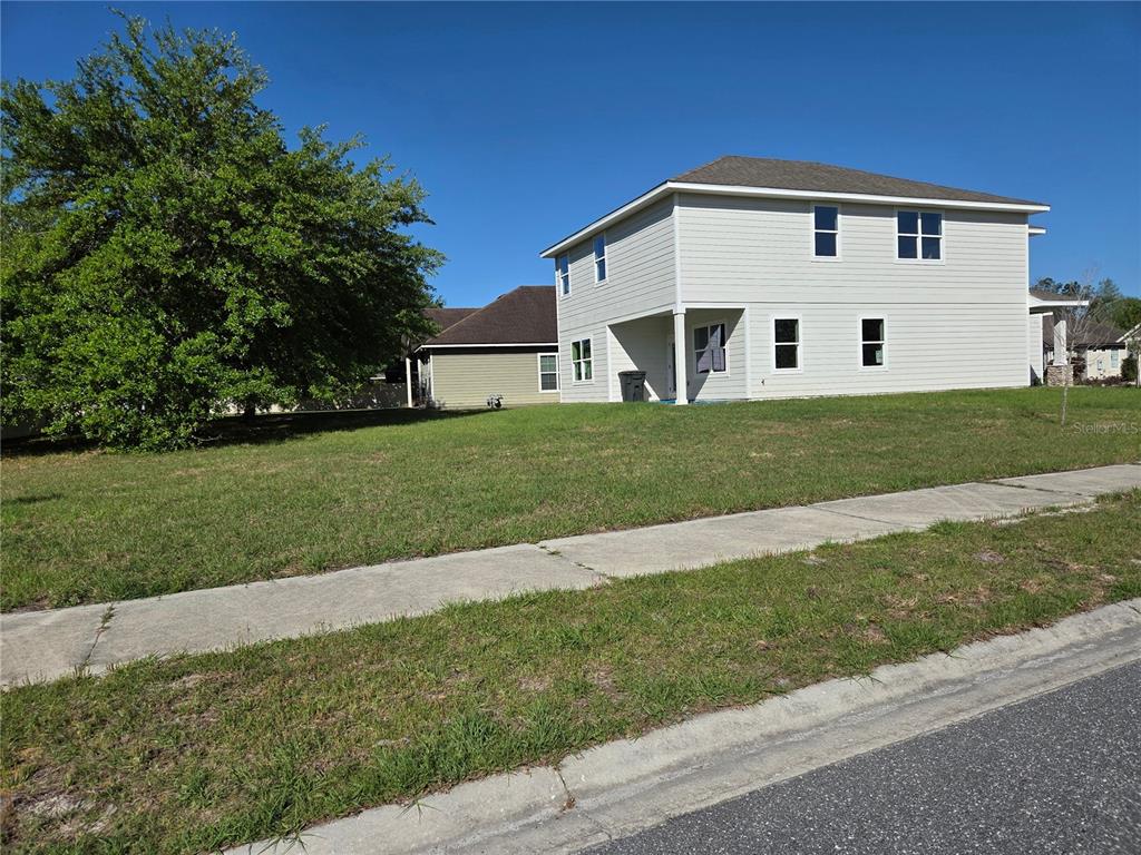 A two-story light-colored house sits on a grassy lot next to a sidewalk — 616 SW ROSEMARY DRIVE, LAKE CITY, FL