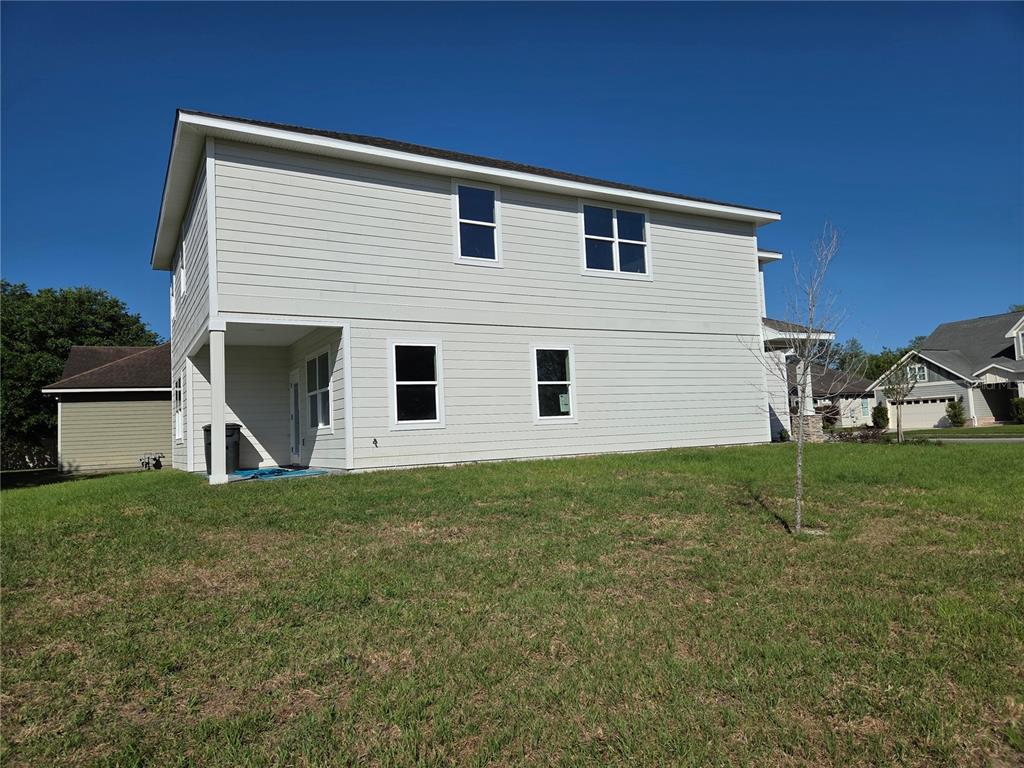 The exterior side view of a two-story house features light-colored siding and several windows — 616 SW ROSEMARY DRIVE, LAKE CITY, FL