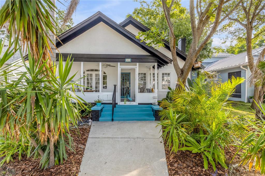 A white bungalow with a dark-trimmed gable roof and a bright blue front porch — 407 MAGNOLIA STREET, NEW SMYRNA BEACH, FL