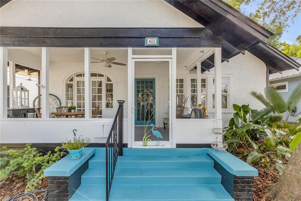 A white house exterior features a screened porch with blue steps and a blue door — 407 MAGNOLIA STREET, NEW SMYRNA BEACH, FL