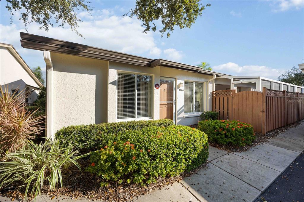 A single-story house exterior features a light-colored facade, a front door, and manicured landscaping — 7206 29TH AVENUE DRIVE W UNIT 2263, BRADENTON, FL