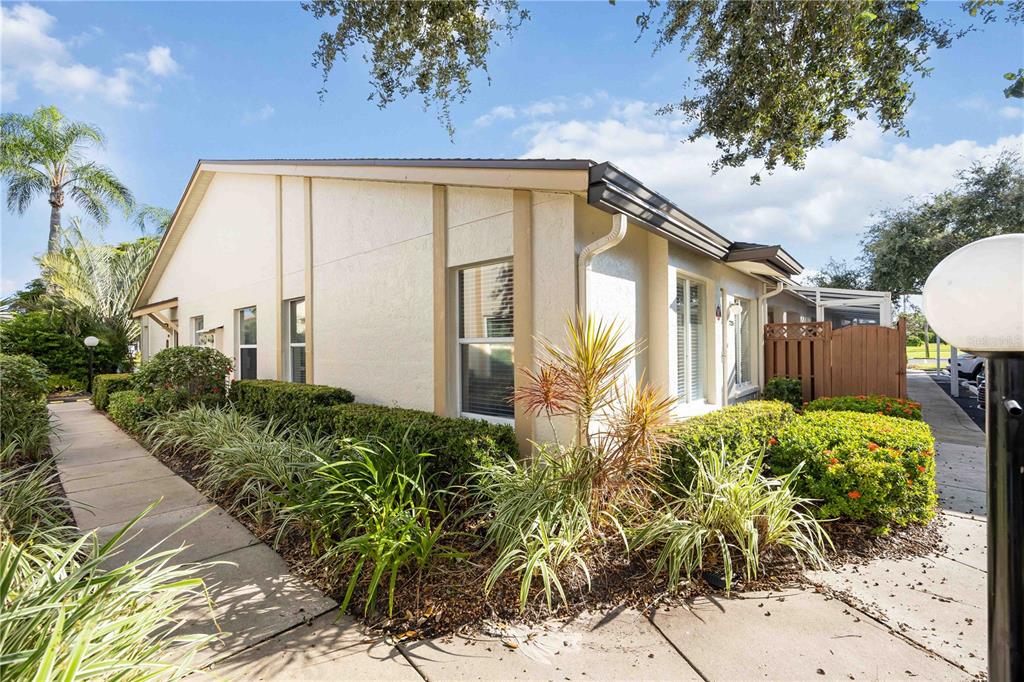 A side view of a single-story stucco building with a sidewalk and landscaped garden — 7206 29TH AVENUE DRIVE W UNIT 2263, BRADENTON, FL