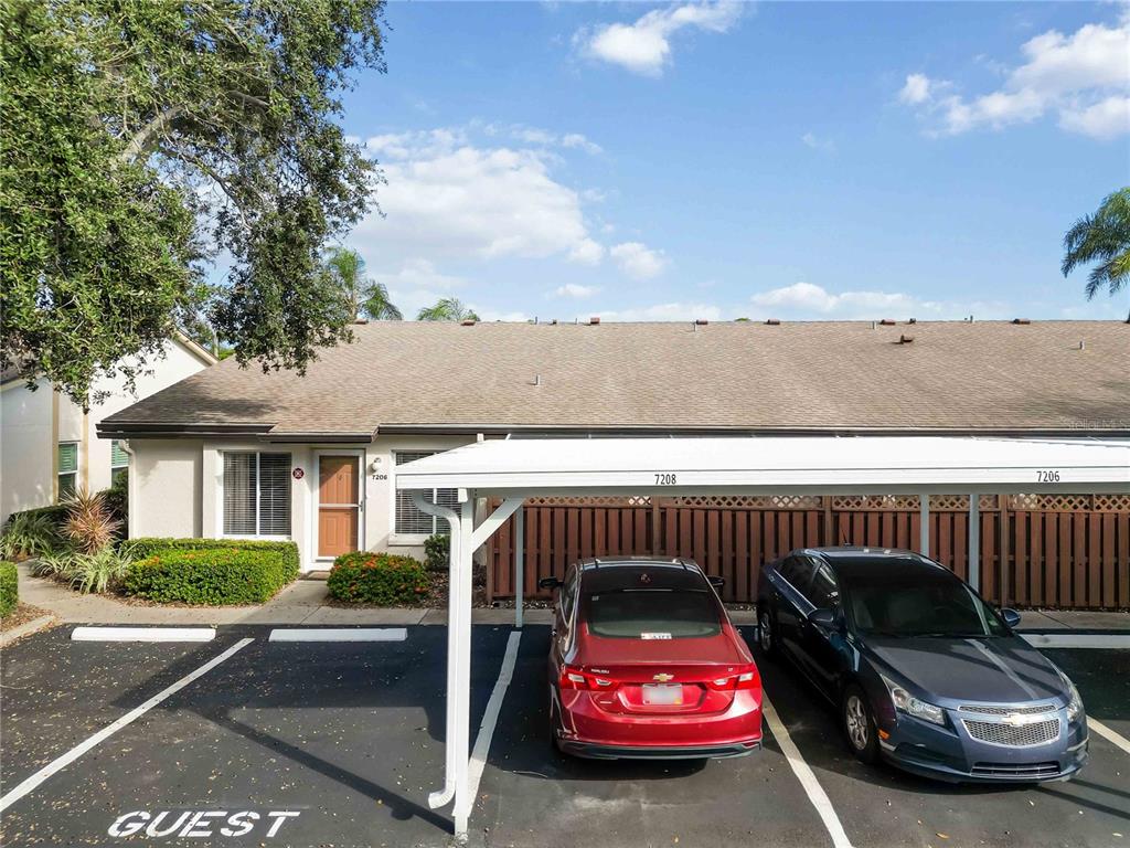 A single-story building exterior features a covered carport with two parked cars and guest parking — 7206 29TH AVENUE DRIVE W UNIT 2263, BRADENTON, FL