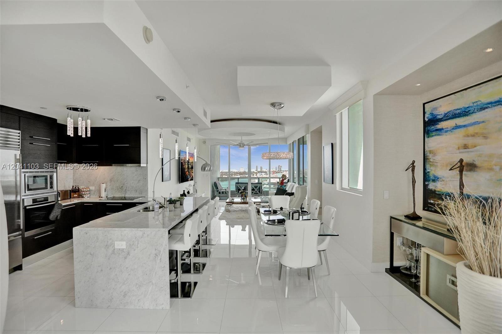 A modern open-concept kitchen and dining area features white marble surfaces and floor-to-ceiling windows — 900 Biscayne Blvd # 2901, Miami FL 33132, MIAMI, FL