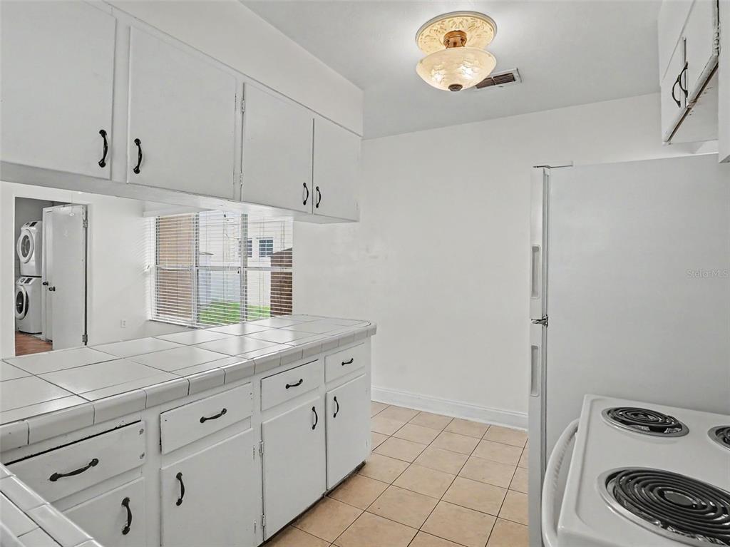 A kitchen features white cabinets, tiled countertops, a white stove, and a tile floor — 1624 HAVEN DRIVE, ORLANDO, FL