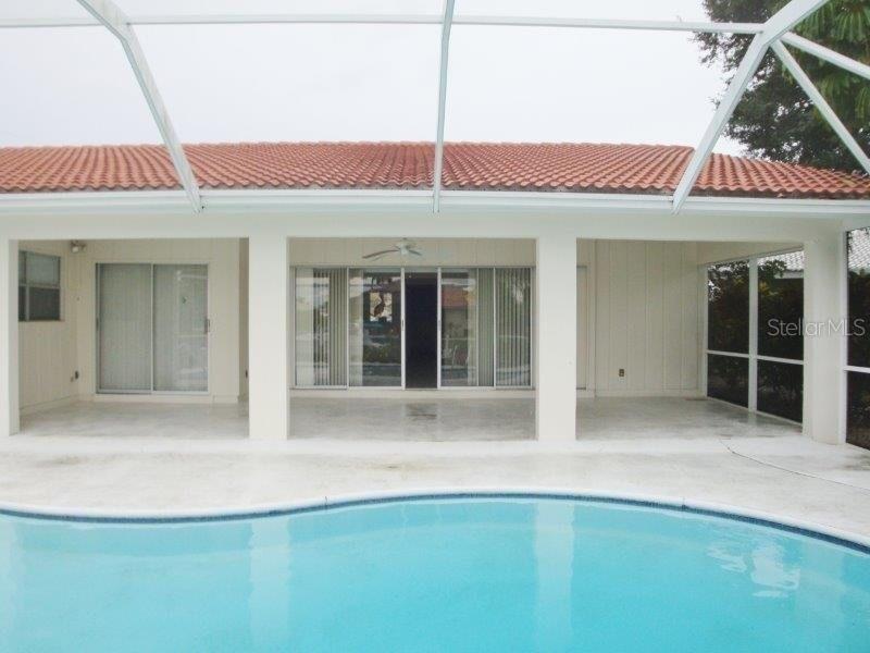 A swimming pool sits in front of a covered patio with sliding glass doors — 910 SANTA BRIGIDA COURT, PUNTA GORDA, FL
