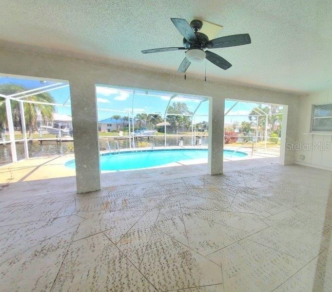 A covered patio with a ceiling fan overlooks a screened-in swimming pool and canal — 910 SANTA BRIGIDA COURT, PUNTA GORDA, FL