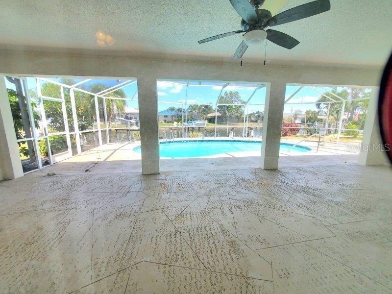 A covered patio with a patterned floor overlooks a swimming pool and a canal — 910 SANTA BRIGIDA COURT, PUNTA GORDA, FL