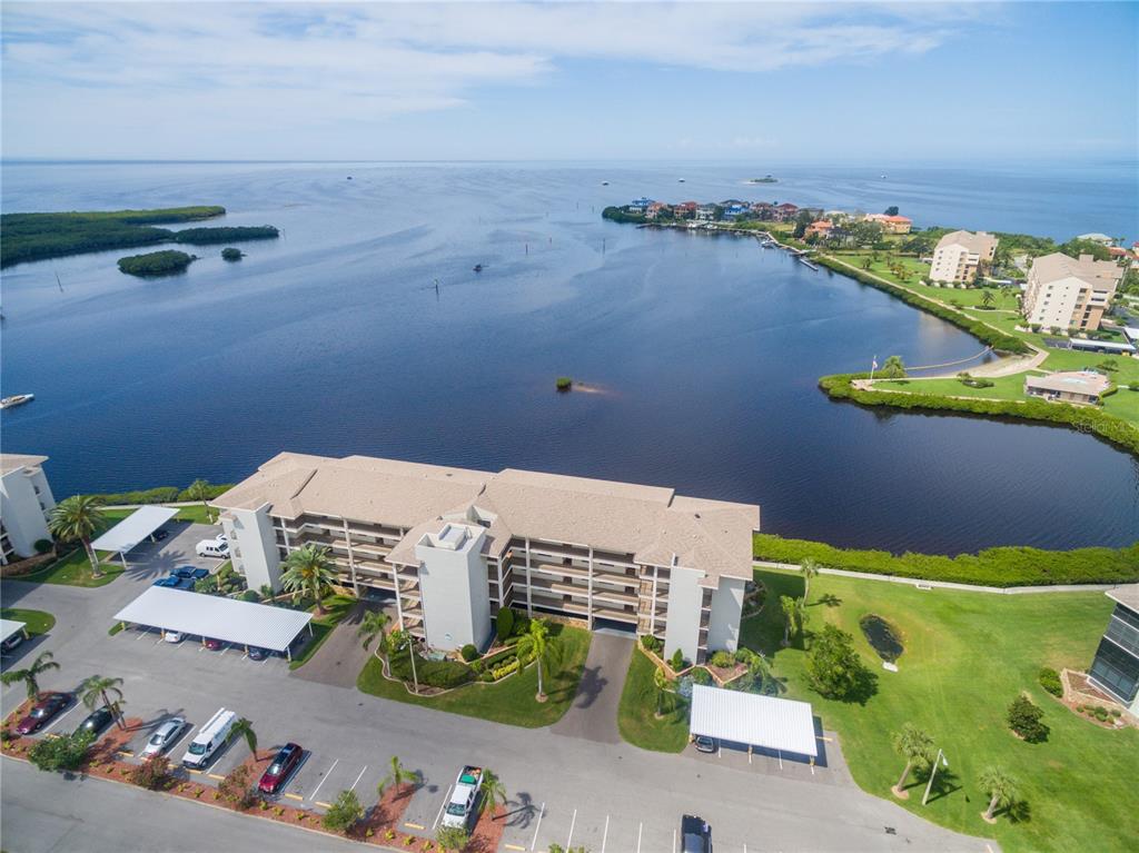 An aerial view of a multi-story apartment building situated next to a large bay — 8211 BRENT STREET UNIT 816, PORT RICHEY, FL