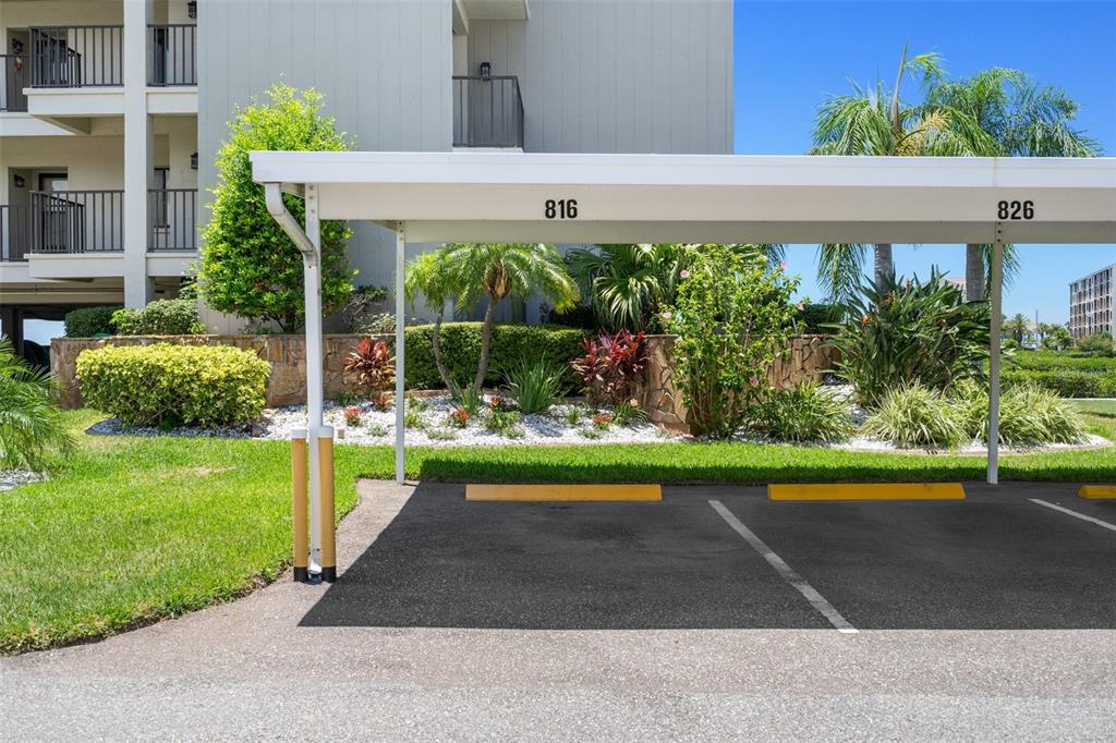 A covered parking area with numbered spaces sits in front of a multi-story apartment building — 8211 BRENT STREET UNIT 816, PORT RICHEY, FL