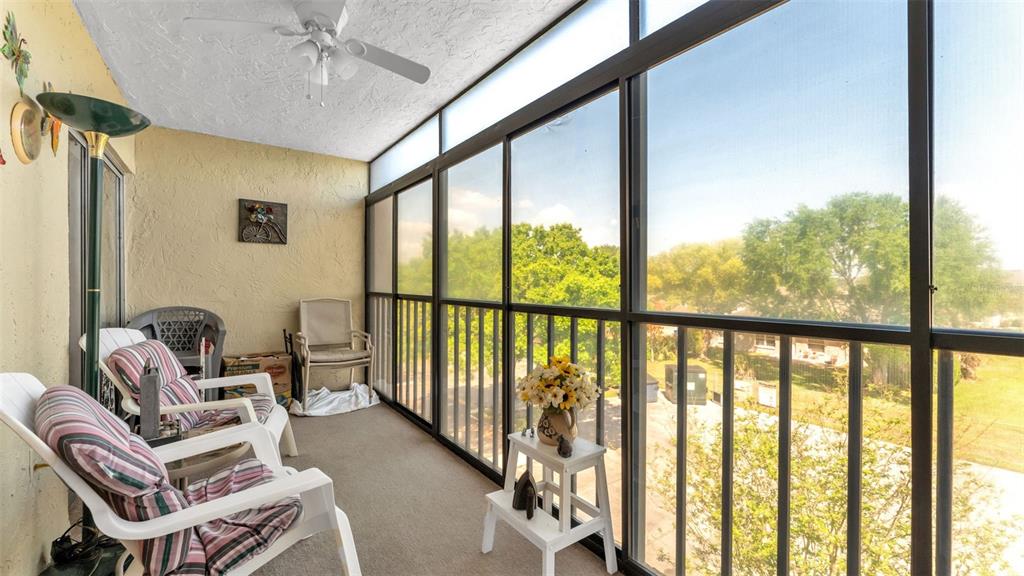 A screened-in balcony with carpeted flooring, white chairs, and a ceiling fan — 1130 N LAKE PARKER AVENUE UNIT C321, LAKELAND, FL