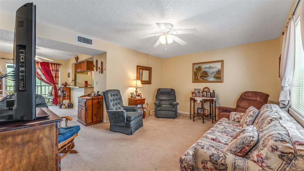 A living room features beige walls, carpeted flooring, a ceiling fan, and several armchairs — 1130 N LAKE PARKER AVENUE UNIT C321, LAKELAND, FL