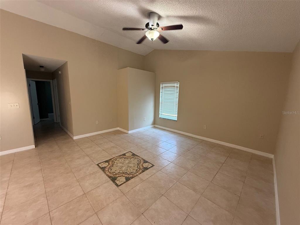 An empty room features beige tile flooring with a decorative inlay and a ceiling fan — 2392 FAIRVIEW ROAD, SPRING HILL, FL