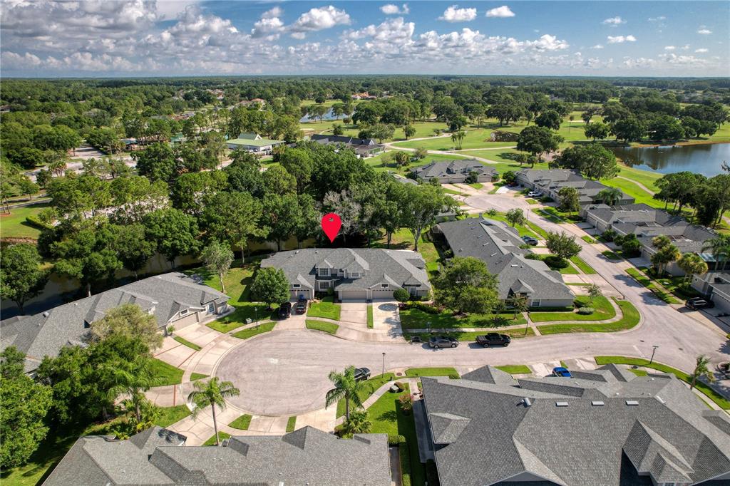An aerial view shows a residential neighborhood with houses, trees, and a nearby pond — 12709 BURMAH COURT, ODESSA, FL