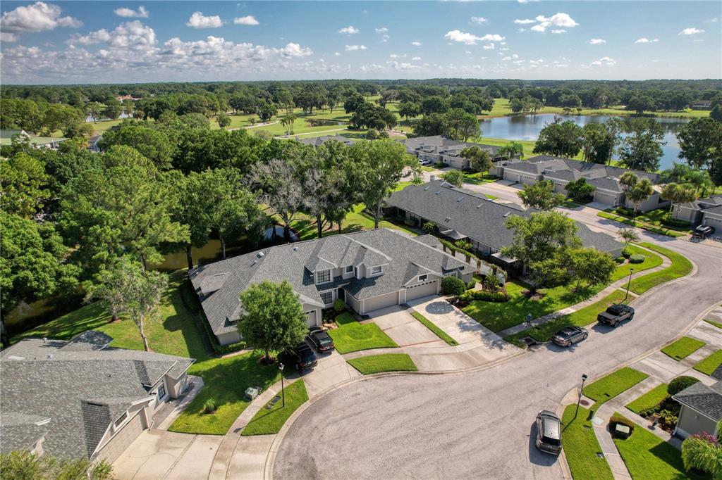 An aerial view shows a residential neighborhood with single-story homes, green lawns, and a lake — 12709 BURMAH COURT, ODESSA, FL