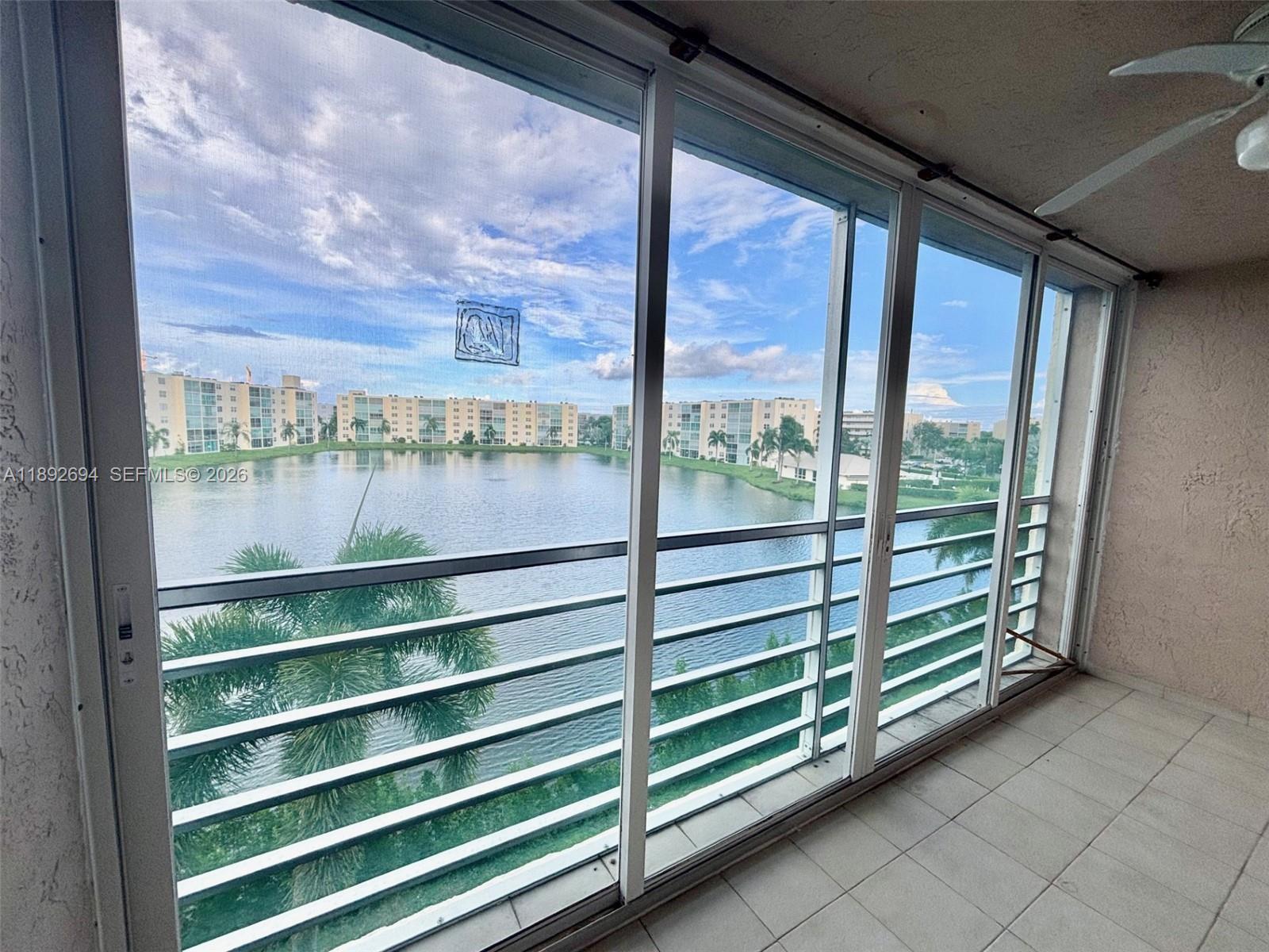 A screened-in balcony overlooks a lake surrounded by multi-story residential buildings — 141 SE 3rd Ave # 402, Dania Beach FL 33004, DANIA BEACH, FL