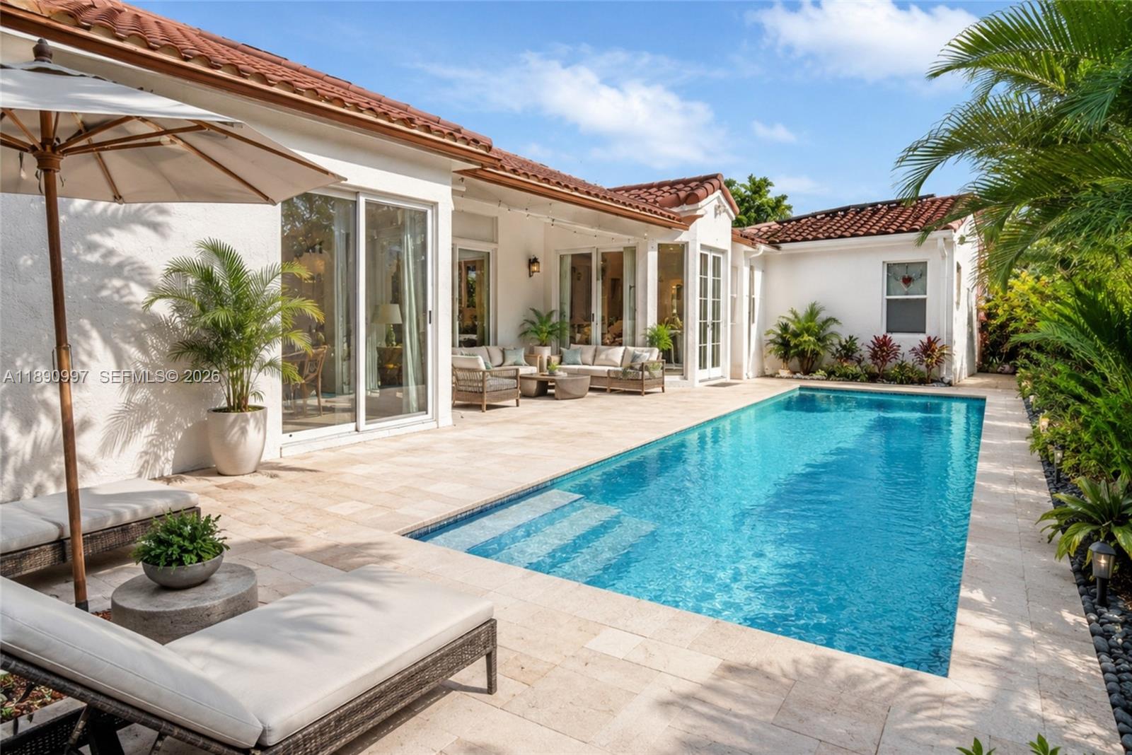 A swimming pool sits on a stone patio next to a white house with tile roofing — 523 Stonemont Dr, Weston FL 33326, WESTON, FL