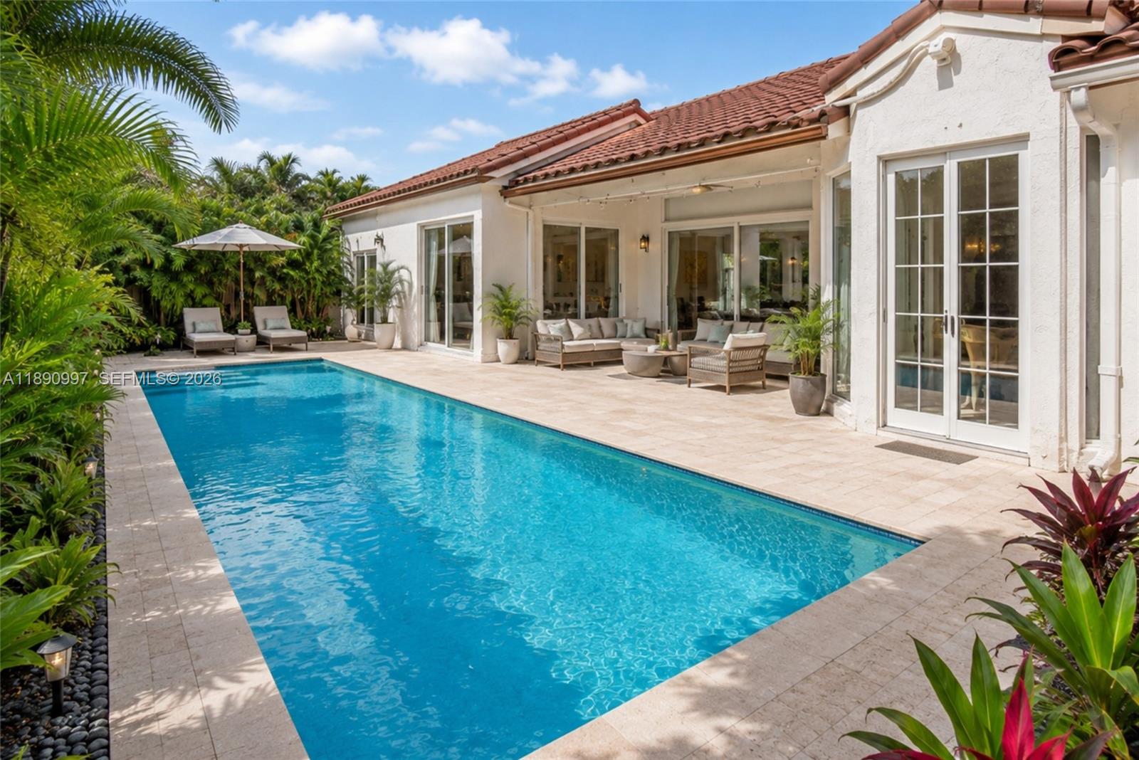 A swimming pool sits on a stone patio next to a white house with glass doors — 523 Stonemont Dr, Weston FL 33326, WESTON, FL