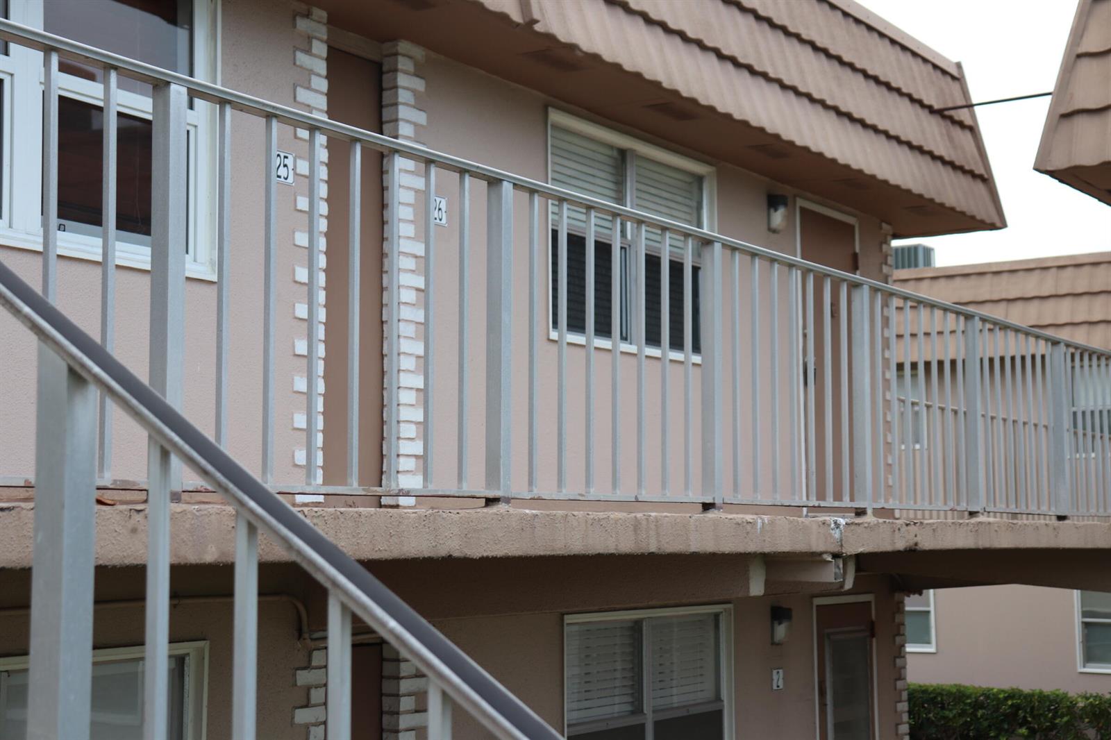 An exterior view of a two-story apartment building with a metal balcony railing and stairs — 26 Brittany # A, Delray Beach FL 33446, DELRAY BEACH, FL