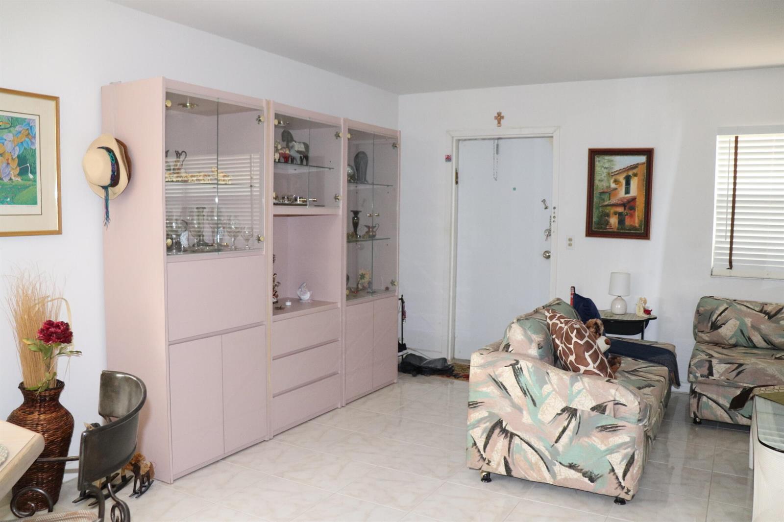 A living room features light tile floors, a large pink display cabinet, and patterned furniture — 26 Brittany # A, Delray Beach FL 33446, DELRAY BEACH, FL