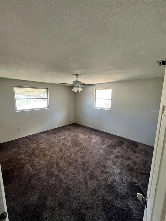 An empty bedroom features dark brown carpeting, light gray walls, and a ceiling fan — 4144 KIBLER LANE, HOLIDAY, FL