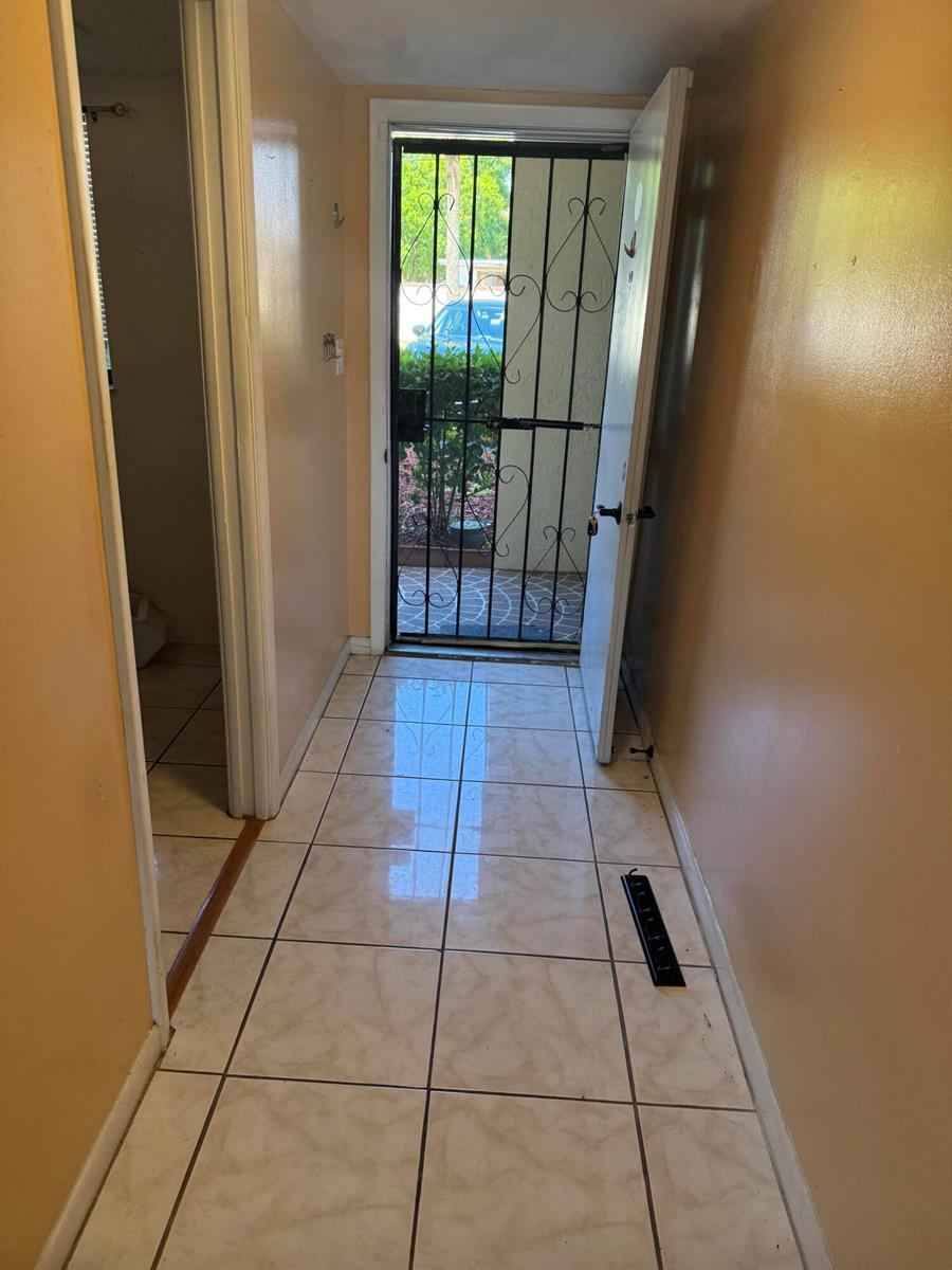 A tiled entryway leads to an open door with a decorative black metal security gate — 2025 Oleander Boulevard # 105, Fort Pierce FL 34982, FORT PIERCE, FL