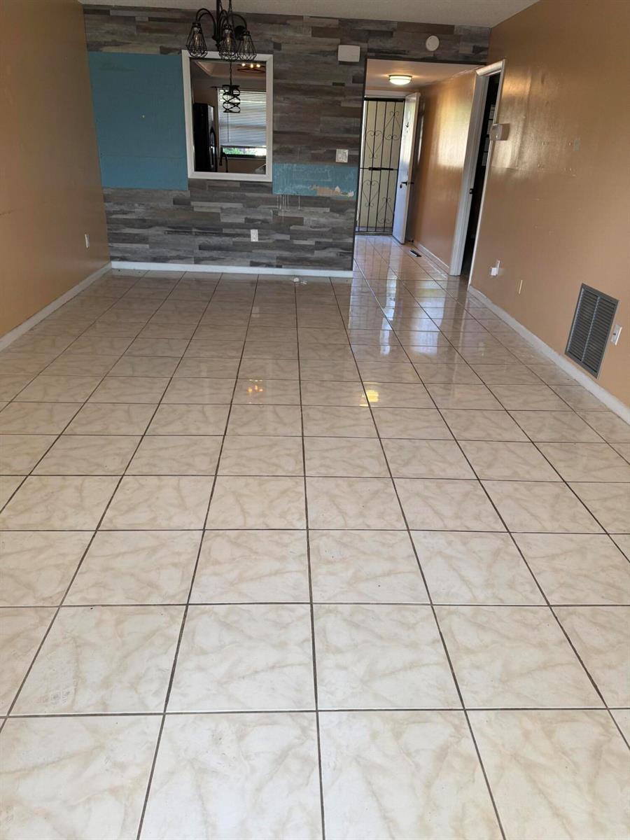 An interior view of a room with beige tiled floors, tan walls, and a wood-paneled accent wall — 2025 Oleander Boulevard # 105, Fort Pierce FL 34982, FORT PIERCE, FL
