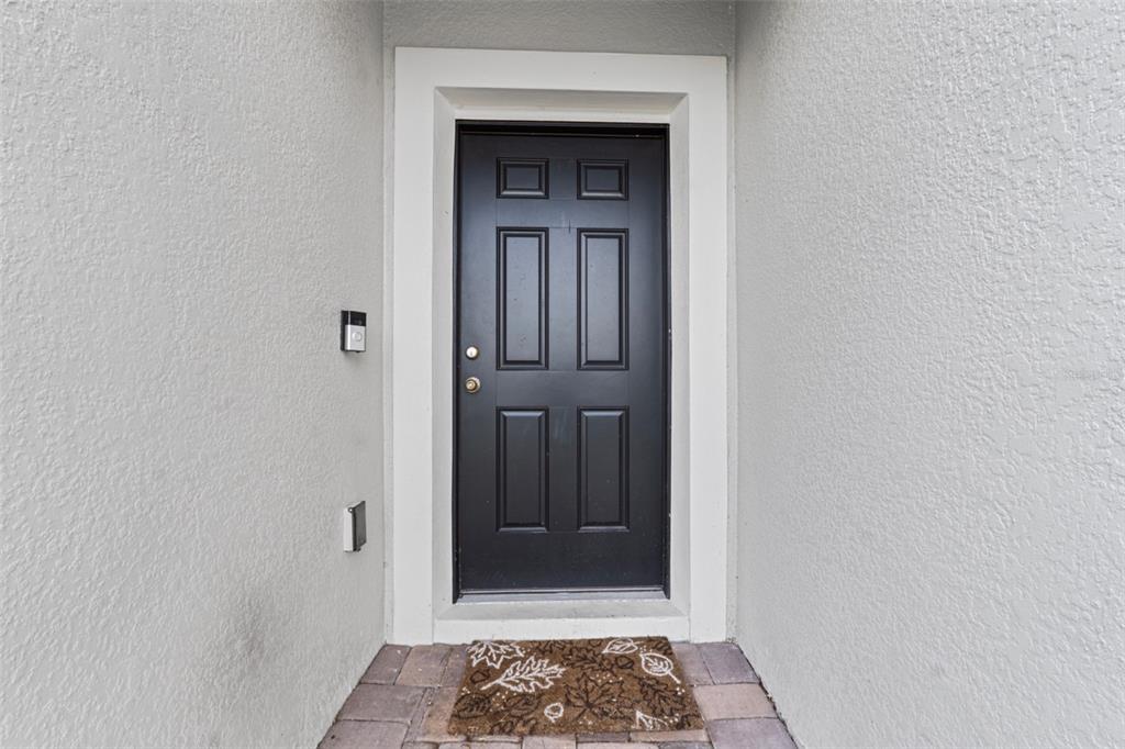 A black front door with a white frame is centered in a stucco entryway — 2621 GLENROCK COURT, KISSIMMEE, FL