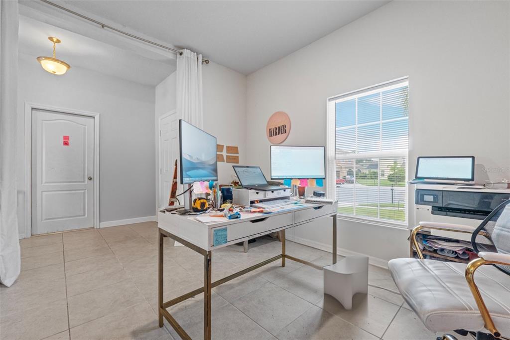 A home office features a desk with multiple monitors, a printer, and tile flooring — 2621 GLENROCK COURT, KISSIMMEE, FL