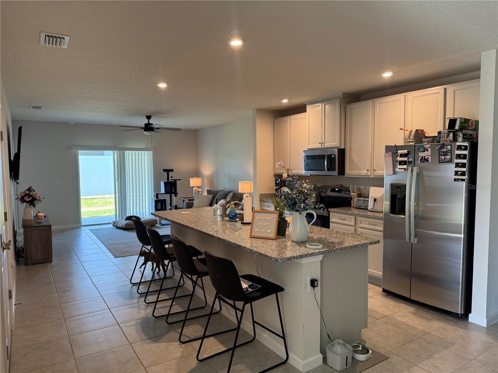 A kitchen with granite countertops and an island overlooks an open-concept living area — 461 VOLTAIRE DRIVE, SPRING HILL, FL