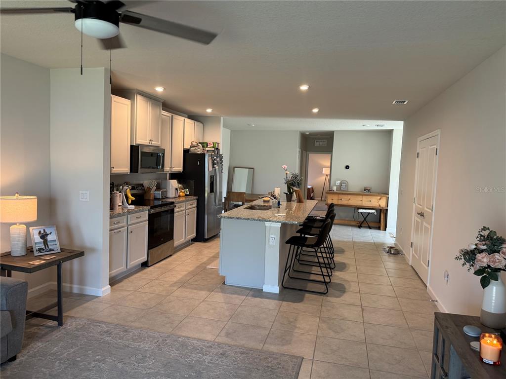 A kitchen features light gray cabinets, granite countertops, a center island, and tile flooring — 461 VOLTAIRE DRIVE, SPRING HILL, FL