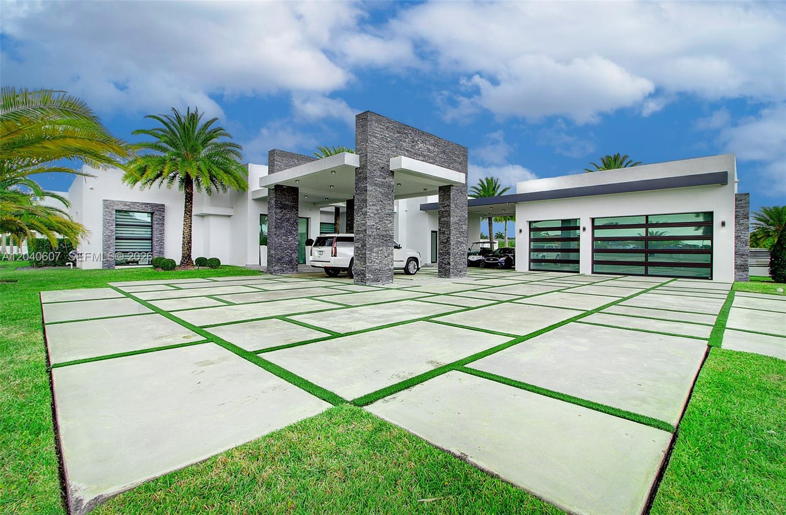 A modern white house features a stone-pillared porte-cochere and a large concrete paver driveway — 13052 NW 102nd Ave, Hialeah Gardens FL 33018, HIALEAH GARDENS, FL