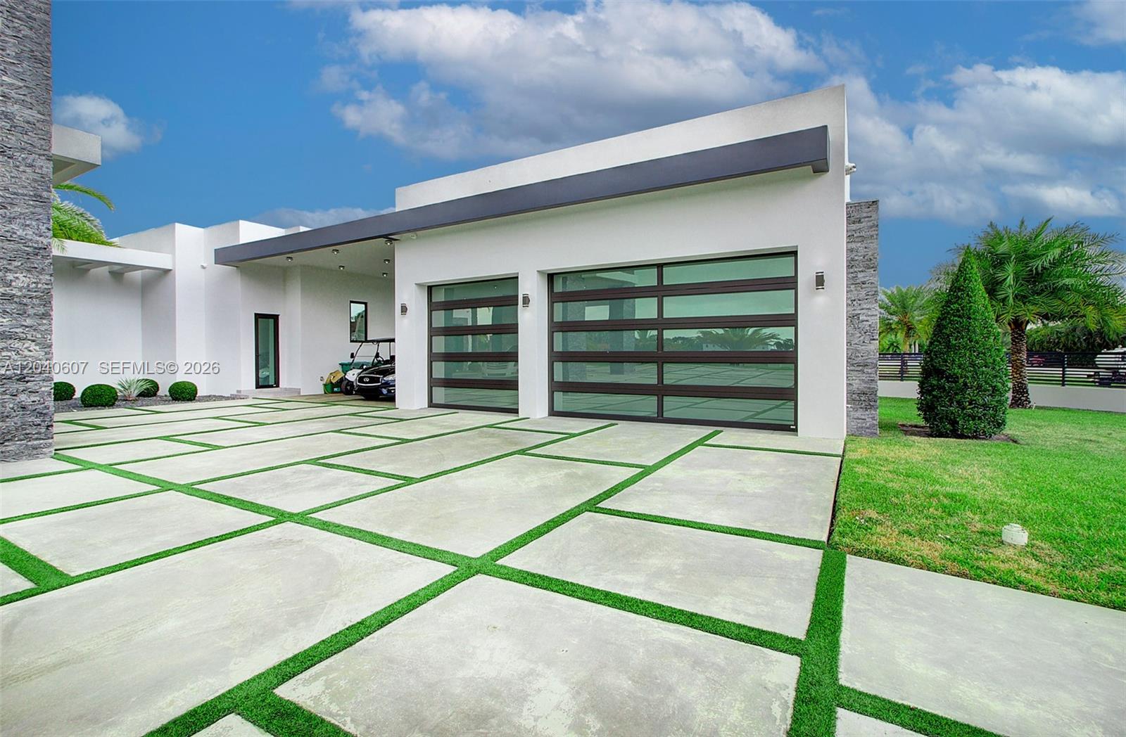 A modern house exterior features a two-car garage with glass doors and a paved driveway — 13052 NW 102nd Ave, Hialeah Gardens FL 33018, HIALEAH GARDENS, FL